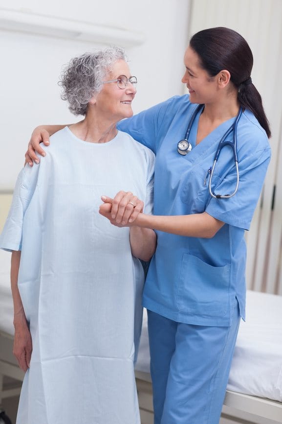 Nurse assisting an elderly patient in hospital ward