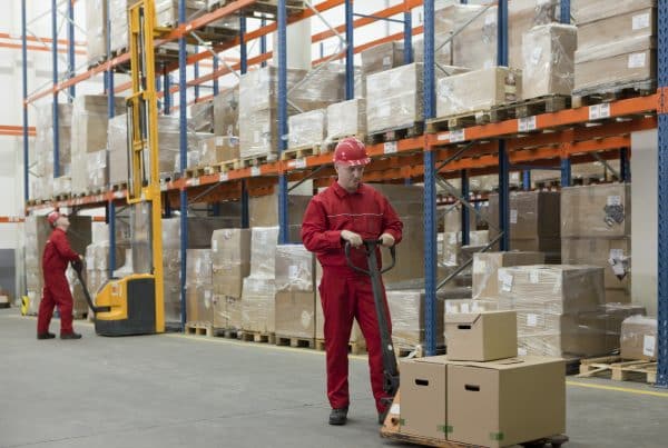 Warehouse workers struggling to organize materials without a motorized trailer dolly
